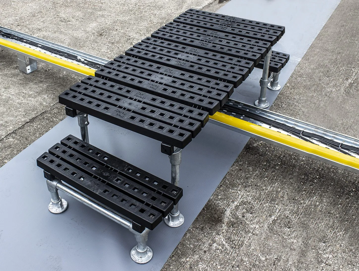 Mini step-over platform crossing pipework on a flat roof