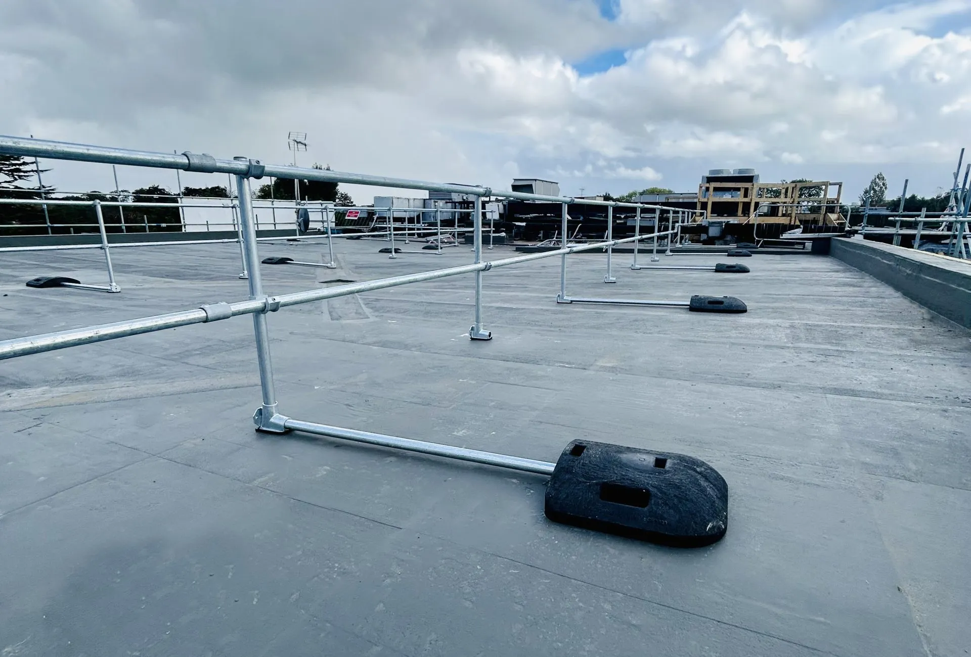Freestanding roof edge protection guardrail with counterweight bases on a flat roof